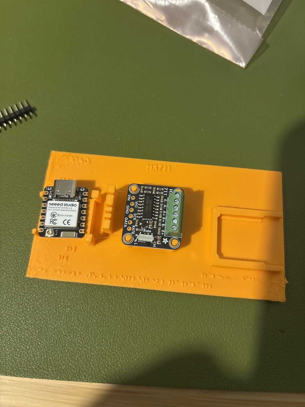The XIAO and the HX711 sitting in an orange printed soldering jig